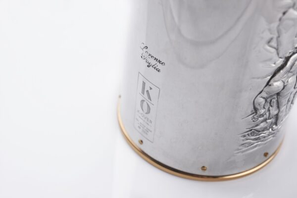 Silver champagne bottle cover with bas-relief inspired by mythological bacchanal scene.