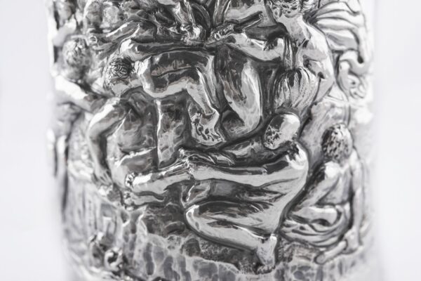 Silver champagne bottle cover with bas-relief inspired by mythological bacchanal scene.