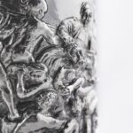 Silver champagne bottle cover with bas-relief inspired by mythological bacchanal scene.