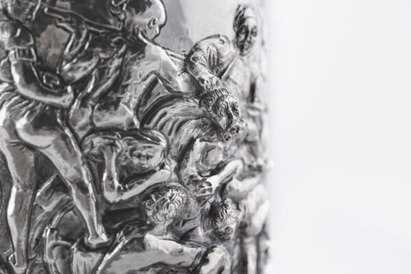 Silver champagne bottle cover with bas-relief inspired by mythological bacchanal scene.