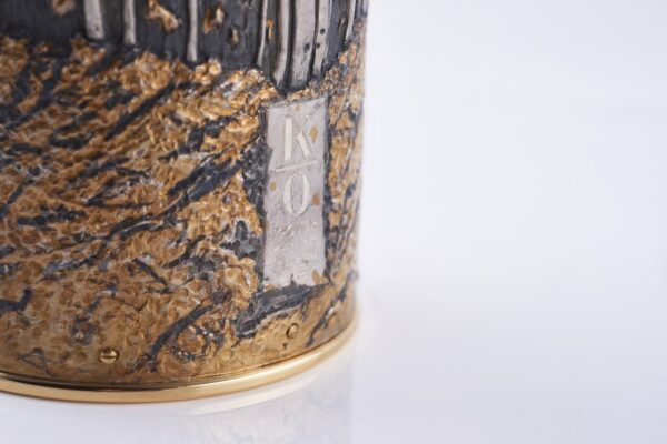 Detail of champagne bottle cover, engraved forest scene in autumn colors.
