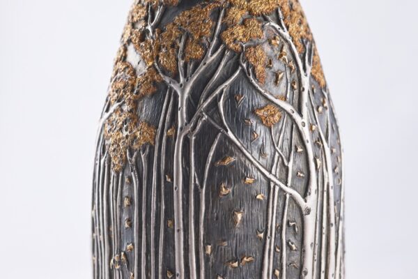 Detail of champagne bottle cover, engraved forest scene in autumn colors.
