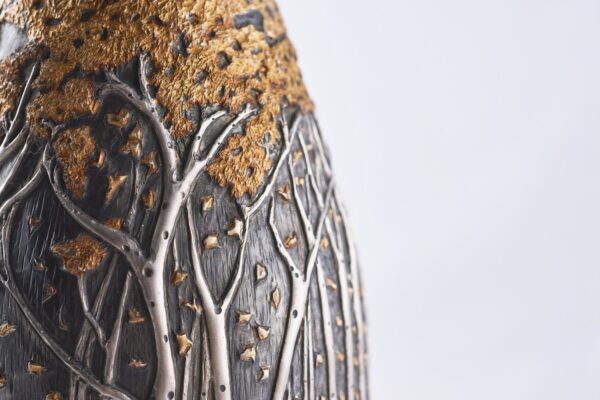 Detail of champagne bottle cover, engraved forest scene in autumn colors.