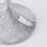 Close-up of a silver wine glass stem with a textured design and a small engraved plaque reading 'KOVER' affixed to the base