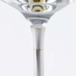 Close-up detail of a wine glass stem, showcasing the transition between the clear glass cup and the smooth silver metal stem. The precision connection highlights the refined craftsmanship and elegant design."
