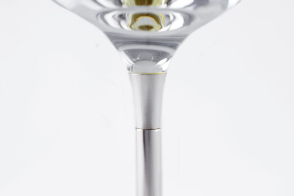 Close-up detail of a wine glass stem, showcasing the transition between the clear glass cup and the smooth silver metal stem. The precision connection highlights the refined craftsmanship and elegant design."