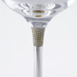 Detail of a luxury wine glass stem, featuring a section encrusted with small diamonds or crystals, set in a silver structure