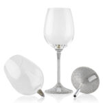 Couple of wine glass with a sleek, modern design. The clear glass cup sits atop a slim metal stem, which transitions into a textured, silver-finished base featuring a small plaque engraved with the word 'KOVER'.