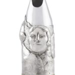 Artistic silver champagne bottle cover, finely engraved with expressive human faces emerging from textured surfaces, creating a sculptural effect that blends contemporary design and traditional craftsmanship.