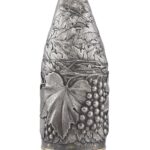 Champagne bottle cover in silver, finely engraved with vine leaves, tendrils, and grape clusters, highlighted by a gold-plated base