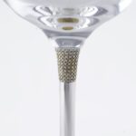 Detail of a luxury wine glass stem, featuring a section encrusted with small diamonds or crystals, set in a silver structure