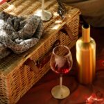 picnic basket, a wine glass and a gold wine bottle cover