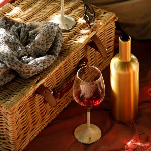 picnic basket, a wine glass and a gold wine bottle cover