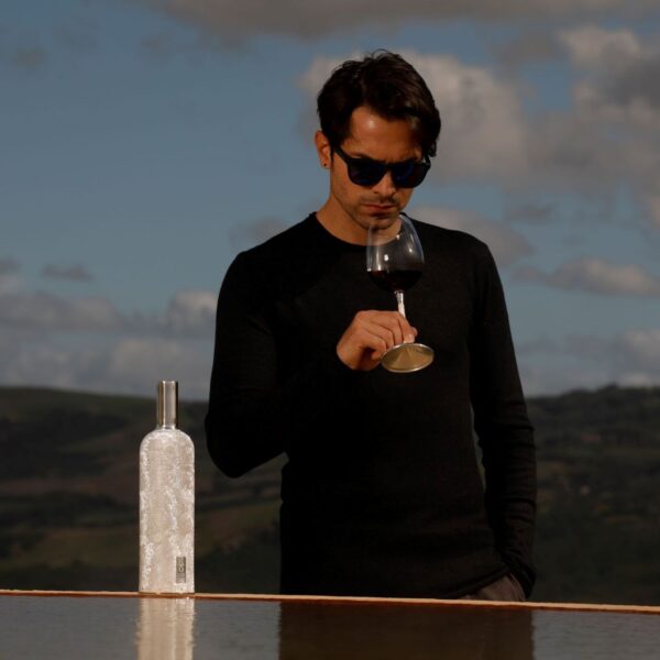 wine bottle cover with wine custom glass, set with a male model. Tuscany Landscape in the background