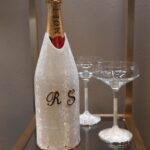 Personalized champagne bottle cover with wedding initials and two champagne glasses