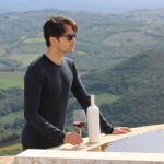 wine bottle cover with wine custom glass, set with a male model. Tuscany Landscape in the background